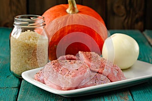 Raw meat, whole pumpkin, onion and rice with pepper mill