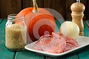 Raw meat, whole pumpkin, onion and rice with pepper mill