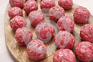 Raw meatballs of beef on a wooden board