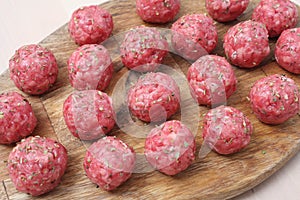 Raw meatballs of beef on a wooden board