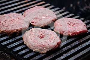 Raw meatballs for burgers are fried on grill. Meat is roasting on BBQ grill outdoor. Heat and smoke dissipate over barbecue photo