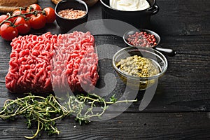 Raw meatballs made from ground beef ingredients, on black wooden table background