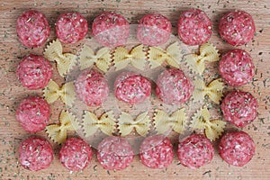 Raw meatballs and pasta bows on a wooden Board