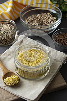 Raw millet groats in glass bowl with variouse cereals on the background. Healthy food, cereals. Uncooked cereals for breakfast