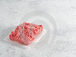 Raw minced beef on light gray cement background