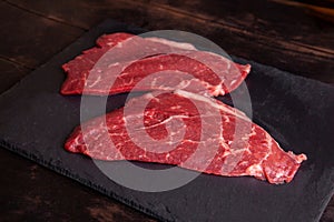 Raw minute steak of marbled beef on a stone slate board