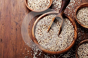 Raw mixed quinoa in bowl on wooden kitchen table top view. Healthy and diet superfood product