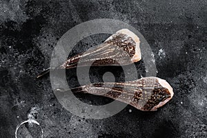 Raw monkfish without a head. Black background. Top view