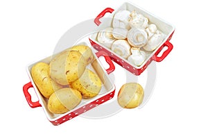 Raw mushrooms and potatoes in red trays, isolated