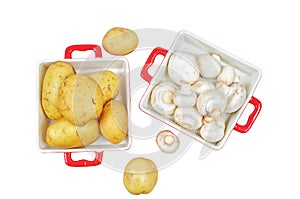 Raw mushrooms and potatoes in red trays, isolated