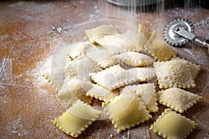 Raw natural ravioli strew with flour on a wooden table