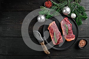 Raw New York striploin beef steak to the Christmas and New Year, on black wooden table background, top view flat lay, with copy