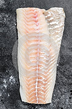 Raw Norwegian skrei cod fish fillet. Black background. Top view