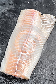 Raw Norwegian skrei cod fish fillet. Black background. Top view