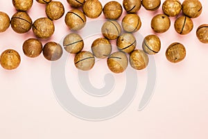 Raw not peeled macadamia nuts on pink background