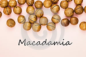 Raw not peeled macadamia nuts on pink background