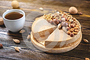 Raw nutty cake decorated with walnut, almond, hazelnut on a dark wooden background. Gluten free and sugar free product