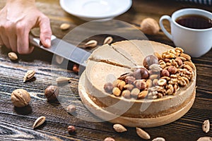 Raw nutty cake decorated with walnut, almond, hazelnut on a dark wooden background. Healthy fresh vegan dessert