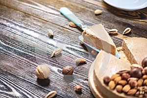 Raw nutty cake decorated with walnut, almond, hazelnut on a dark wooden background. Healthy fresh vegan dessert