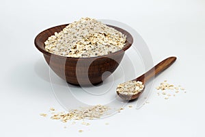 Raw oat flakes in a clay plate on a white background