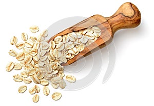 Raw oatmeal in the wooden scoop, isolated on white, top view