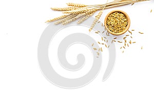 Raw oats in bowl near sprigs of wheat on white background top view copy space