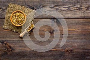 Raw oats in bowl and scoop on dark wooden background top view copy space