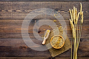 Raw oats in bowl and scoop on dark wooden background top view copy space