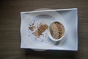 Raw organic Buckwheat in ceramic bowl on white plate