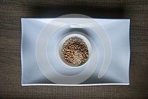 Raw organic Buckwheat in ceramic bowl on white plate