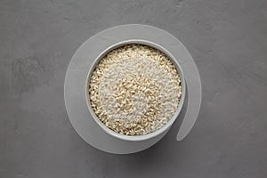 Raw Organic Carnaroli Rice in a Bowl on a gray background, top view. Overhead, from above, flat lay