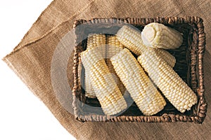 Raw organic corn in wicker basket close up isolated on white background