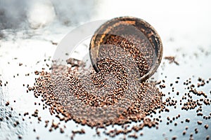 Raw organic herbal spice Mustard seeds or sarso or rai or Brassica nigra, in a clay bowl on wooden surface.