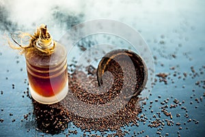 Raw organic herbal spice Mustard seeds or sarso or rai or Brassica nigra, in a clay bowl on wooden surface with its extracted esse