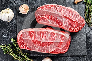 Raw organic meat Twagyu oyster top blade steak. Black background. Top view