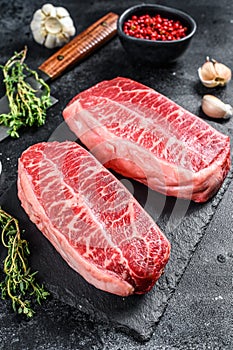 Raw organic meat Twagyu oyster top blade steak. Black background. Top view