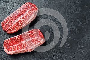 Raw organic meat Twagyu oyster top blade steak. Black background. Top view. Copy space