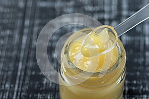 Raw organic royal jelly in a small bottle with litte spoon on small bottle on black background,