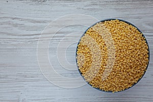 Raw Organic Stelline Pasta in a Bowl on a white wooden background, top view. Flat lay, overhead, from above. Copy space