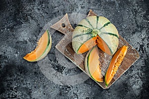 Raw Organic Tuscan Melon Cantaloupe. Yellow pieces of melon on a wooden board on a dark background, banner, menu, recipe place for