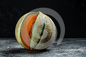 Raw Organic Tuscan Melon Cantaloupe. Yellow pieces of melon on a wooden board on a dark background, banner, menu, recipe place for