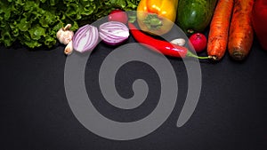 Raw organic vegetables with fresh ingredients for healthily cooking on dark vintage background, top view. Vegan or diet food