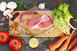 Raw organic vegetables with fresh ingredients for healthy cooking on dark backgroundRaw meat.