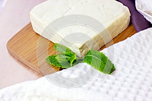 Raw organic vegetarian tofu slices with fresh mint on wooden background.