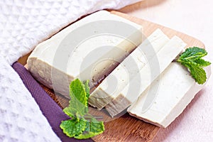 Raw organic vegetarian tofu slices with fresh mint on wooden background.