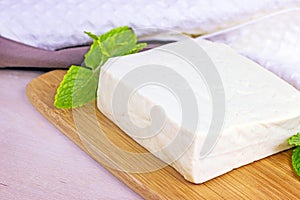 Raw organic vegetarian tofu slices with fresh mint on wooden background.