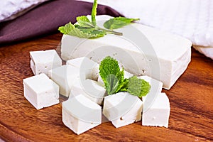 Raw organic vegetarian tofu slices with fresh mint on wooden background.