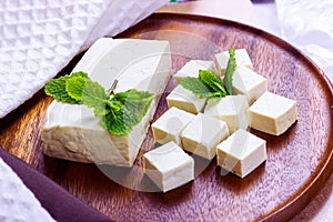 Raw organic vegetarian tofu slices with fresh mint on wooden background.