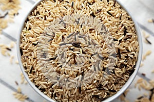 Raw Organic Wild Rice in a Bowl on a white wooden background, top view
