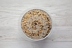 Raw Organic Wild Rice in a Bowl on a white wooden background, top view